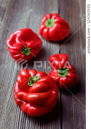 Several fresh red sweet bell peppers on rustic wooden table 124342910