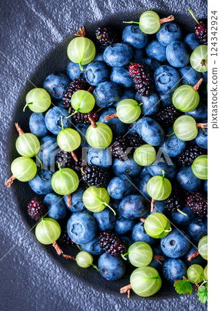 Top view on black plate filled with fresh mixed berries, 124342924
