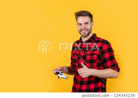 new technology. computer game. young handsome guy in checkered shirt with thumb up. stylish male wear casual clothes. bearded man with bristle play video game with remote. fashion and beauty new technology. computer game. young handsome guy in checkered shirt with thumb up. stylish male wear casual clothes. bearded man with bristle play video game with remote. fashion and beauty 124343139
