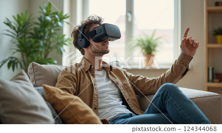 Virtual reality, young man enjoying VR headset while sitting on cozy sofa 124344068