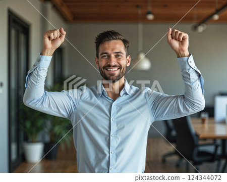 Portrait of successful joyful man inside office at workplace. Worker looking at camera and holding hands up celebrating victory and successful 124344072