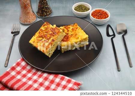 Slices of baked Round Borek cheese pie in kitchen tray with herbs. Dark background. Top view. Copy space 124344510
