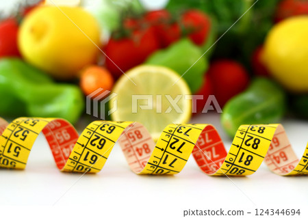 diet concept with measuring tape . fresh vegetables on a white background. Selective focus. 124344694