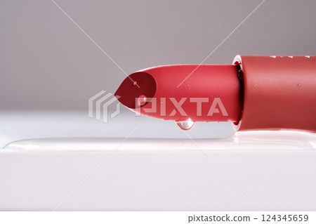 Classic lipstick with drops of water on a neutral background. 124345659