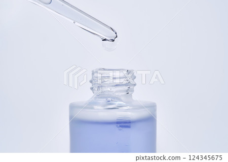 The blue serum drips from the dropper into the bottle. The blue serum drips from the dropper into the bottle. 124345675