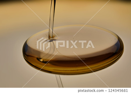 Texture of pouring cosmetic oil on a golden background. Texture of pouring cosmetic oil on a golden background. 124345681