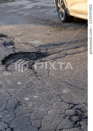 potholes in the road, holes in the asphalt on the roadway or highway.  124345802
