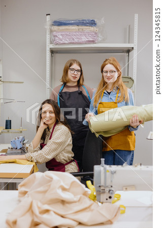 Three female seamstresses work for production of clothing. industrial equipment sewing machines. 124345815