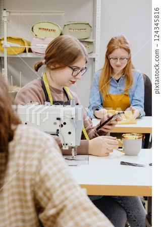 Three women sew in workshop at clothing factory. industrial equipment sewing machines. 124345816