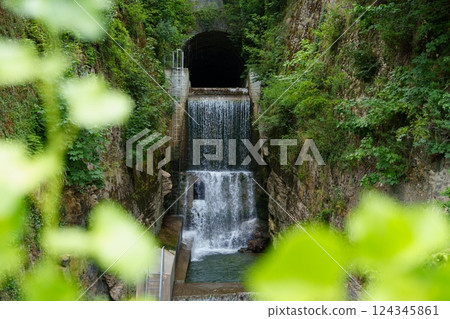 A Majestic Waterfall Surrounded by Lush Green Forest and an Enigmatic Cave Entrance Nearby A Majestic Waterfall Surrounded by Lush Green Forest and an Enigmatic Cave Entrance Nearby 124345861