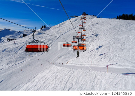 Scenic View of a Red and White Ski Lift Ascending a Snow-Covered Mountain in the Alps, Austria 124345880