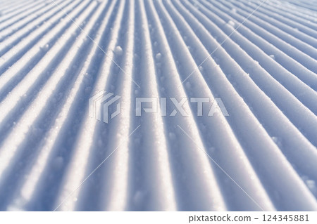 Freshly groomed corduroy ski slope with tracks from skis and poles 124345881