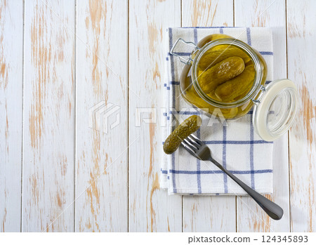 Tasty marinated cucumbers in jar on a wooden table, top view. 124345893