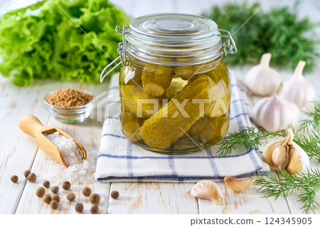 Glass jar of pickled cucumbers and ingredients on wooden table. Marinated cucumbers gherkins. Pickles with dill, salt and garlic. Glass jar of pickled cucumbers and ingredients on wooden table. Marinated cucumbers gherkins. Pickles with dill, salt and garlic. 124345905