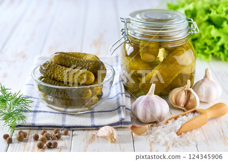 Glass jar of pickled cucumbers and ingredients on wooden table. Marinated cucumbers gherkins. Pickles with dill, salt and garlic. 124345906