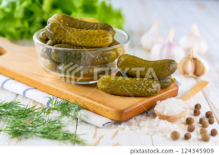 Glass jar of pickled cucumbers and ingredients on wooden table. Marinated cucumbers gherkins. Pickles with dill, salt and garlic. 124345909