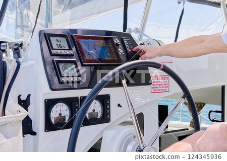 Modern Yacht Dashboard Control Panel with Navigation Features and Steering Wheel in Use Modern Yacht Dashboard Control Panel with Navigation Features and Steering Wheel in Use 124345936