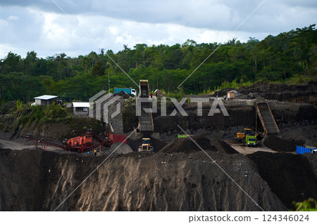 A stone quarry in Indonesia. Large equipment such as bulldozers and dump trucks are working on the site. 124346024