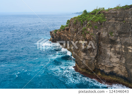 Cinematic aerial landscape shots of the beautiful island of Nusa Penida. Huge cliffs by the shoreline and hidden dream beaches with clear water and foaming wave. 124346043