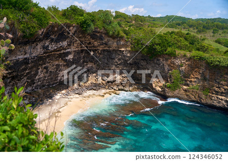 Cliff broken by wave of ocean formed perfect paradise untouched beach. Natural azure bathing pool in the rock. Angel's Billabong is popular tourist destination on island of Nusa Penida in Indonesia. Cliff broken by wave of ocean formed perfect paradise untouched beach. Natural azure bathing pool in the rock. Angel's Billabong is popular tourist destination on island of Nusa Penida in Indonesia. 124346052