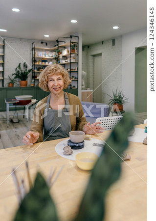 Senior woman enjoying ceramics class, crafting handmade pottery with enthusiasm Senior woman explores new interests, proving lifelong learning has no limits 124346148