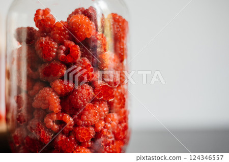 Close-up of raspberries in a glass jar on a white background 124346557