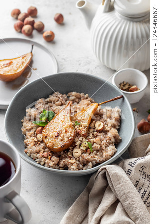 Wholegrain oatmeal porridge with caramelized pear, nuts and honey on white table, healthy food for breakfast Wholegrain oatmeal porridge with caramelized pear, nuts and honey on white table, healthy food for breakfast 124346667