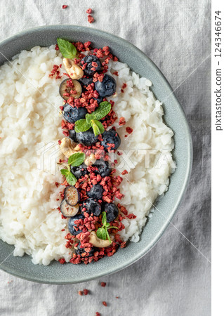 Rice porridge with blueberries, dried raspberries and nuts on a linen tablecloth, hot and healthy breakfast isolated close up 124346674