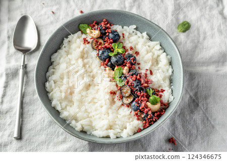 Rice porridge with blueberries, dried raspberries and nuts on a linen tablecloth, hot and healthy breakfast isolated close up Rice porridge with blueberries, dried raspberries and nuts on a linen tablecloth, hot and healthy breakfast isolated close up 124346675