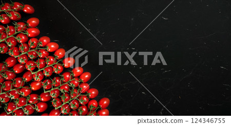 Group of small red cherry tomatoes on black marble like board, overhead shot with space for text right side 124346755