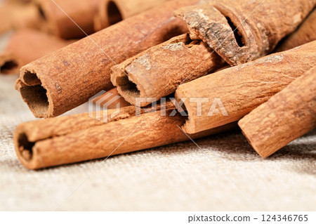 Closeup macro photo - Heap of cinnamon bark sticks on linen tablecloth. 124346765