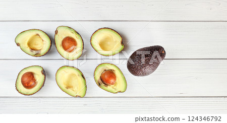 Ripe avocado halves, some with seeds arranged on white boards table, view from above Ripe avocado halves, some with seeds arranged on white boards table, view from above 124346792