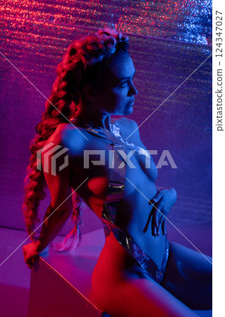Woman poses with silver tape body art in lingerie under colorful lights Woman poses with silver tape body art in lingerie under colorful lights 124347027