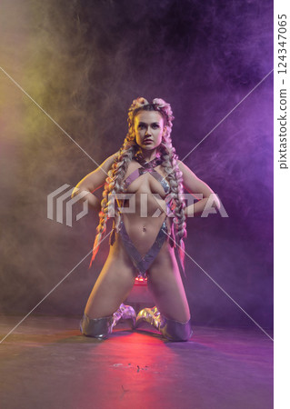 Woman in lingerie displays silver body art at a lively studio 124347065