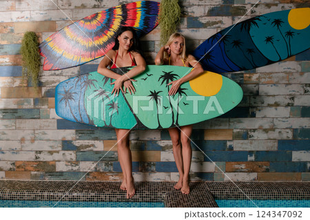 Elegant women posing in lingerie with colorful surfboards in a stylish setting 124347092