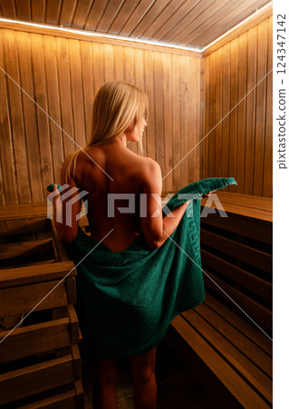 Woman poses in lingerie inside a cozy wooden sauna room during evening time Woman poses in lingerie inside a cozy wooden sauna room during evening time 124347142