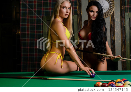 Two women posing in lingerie while playing billiards in an elegant setting 124347143