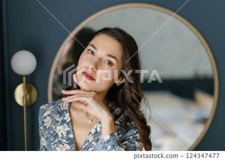 Woman wearing pajamas posing in elegant bedroom with blue walls 124347477