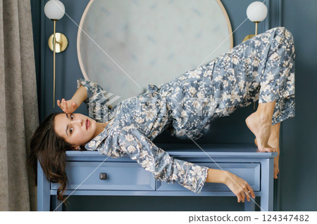 Woman wearing pajamas posing in elegant bedroom with blue walls Woman wearing pajamas posing in elegant bedroom with blue walls 124347482