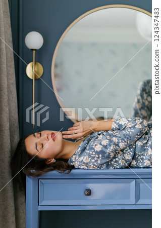 Woman wearing pajamas posing in elegant bedroom with blue walls 124347483