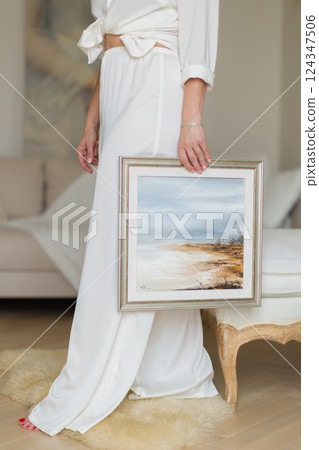 A woman is holding a beautiful painted picture in her hands. 124347506