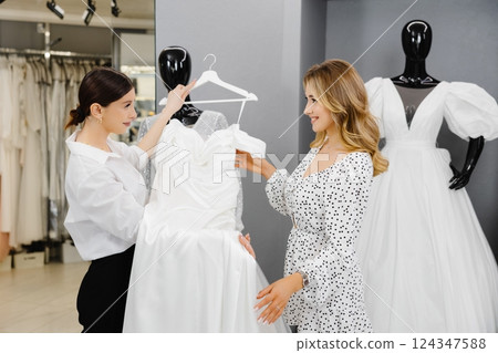 Young woman choosing wedding dress in salon. The bride-to-be came to a wedding dress salon to buy a dress 124347588