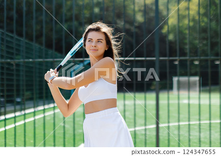 Young female tennis player holding racket posing on court Young female tennis player holding racket posing on court 124347655