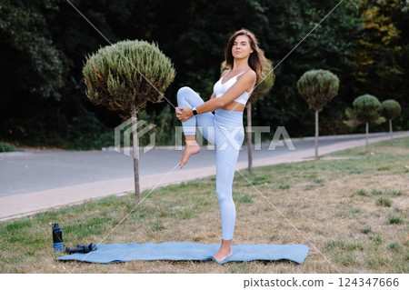 Young woman practicing yoga in a park, holding balancing pose Young woman practicing yoga in a park, holding balancing pose 124347666