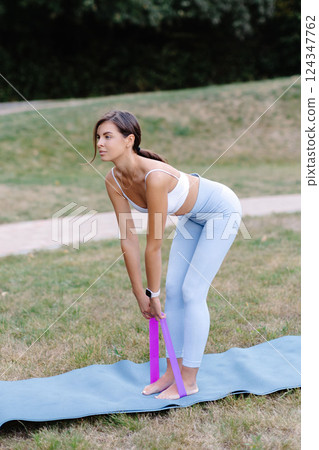 Young woman exercising with resistance band in a park Young woman exercising with resistance band in a park 124347762