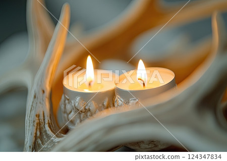 Close-up of a rustic antler candle holder with burning candles, creating a warm and cozy atmosphere. 124347834