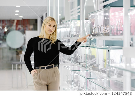 Woman choosing jewelry in a store pointing at glass display 124347848