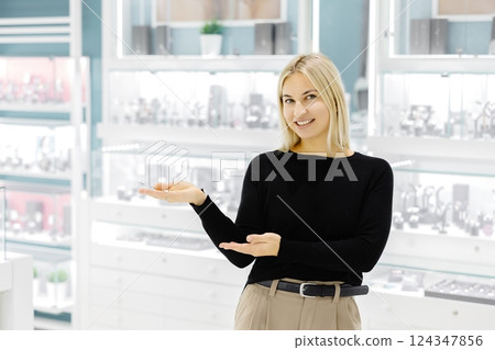 Smiling shop assistant showing jewelry in a jewelry store 124347856