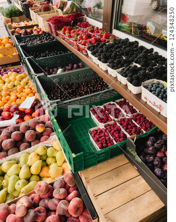 Fresh Seasonal Fruits Displayed at Local Market. Colorful arrangement of various ripe fruits arranged in crates and containers at vibrant farmers market, abundance of summer produce. First-person view 124348250