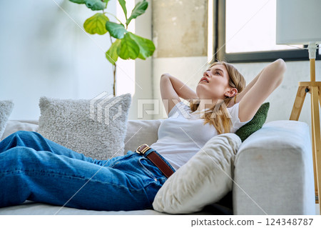 Happy relaxed serene young woman sitting at home on the couch 124348787